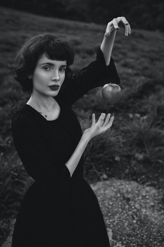 a white woman witch suspending an apple, black and white pic